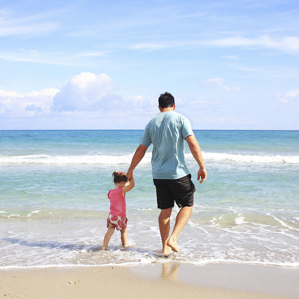 Padre e hija paseando por la playa